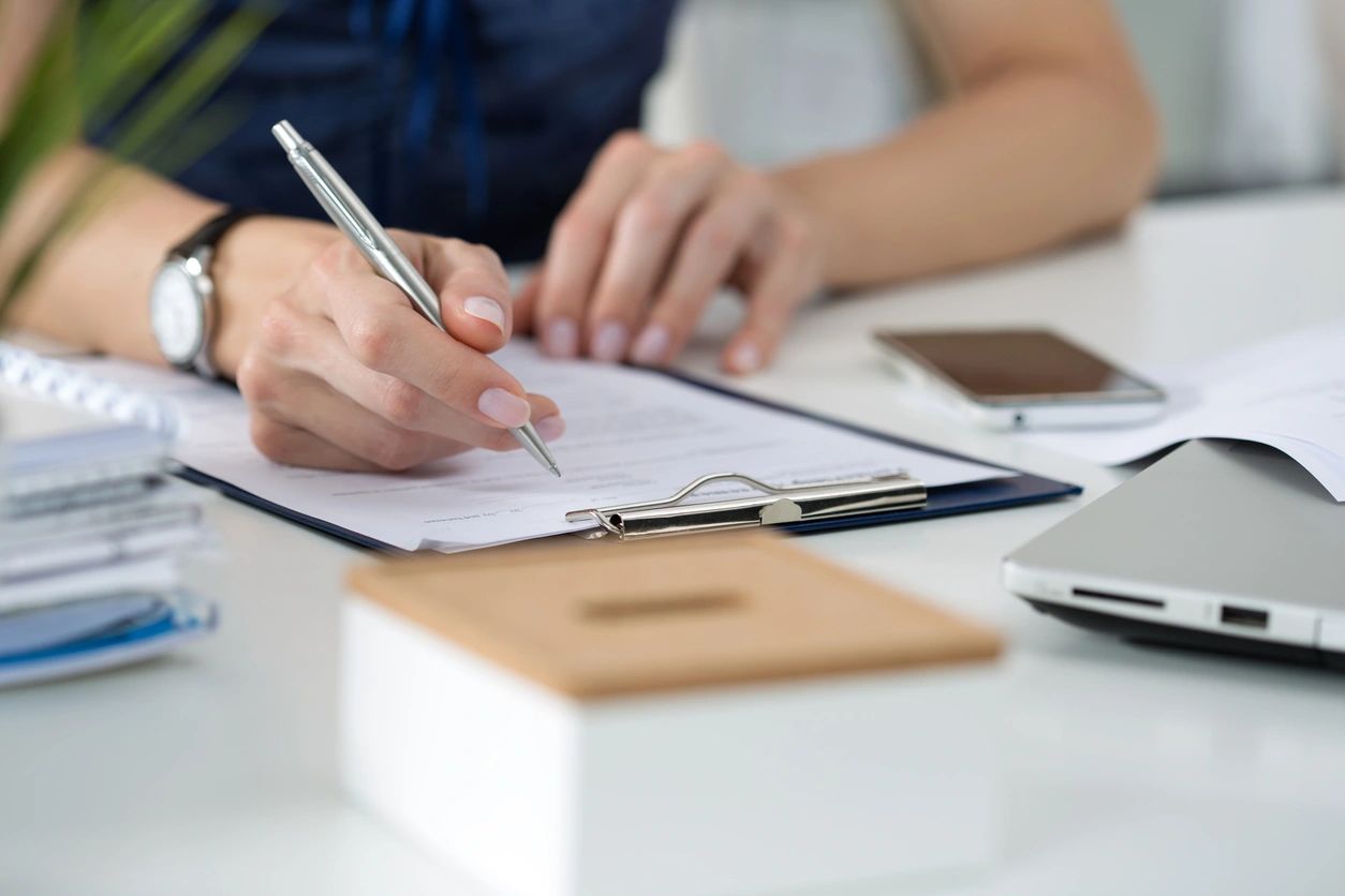 person signing documents on desk